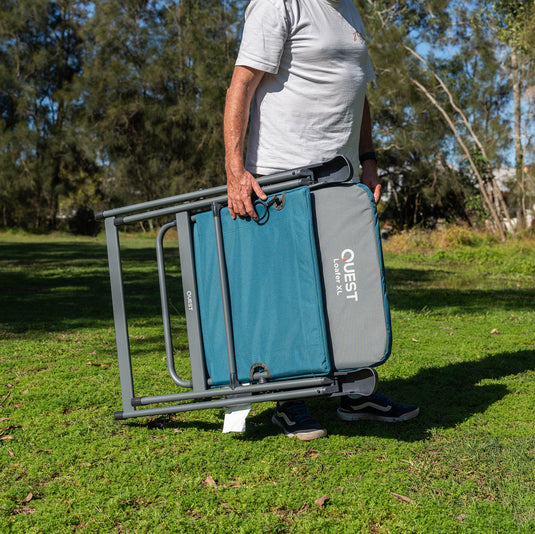 Person holding a Quest Loafer Jumbo Reclining Chair in a grassy outdoor setting