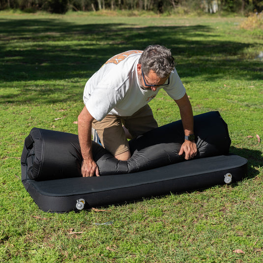 Rolling up a Quest Dreamlite camping mattress on grass
