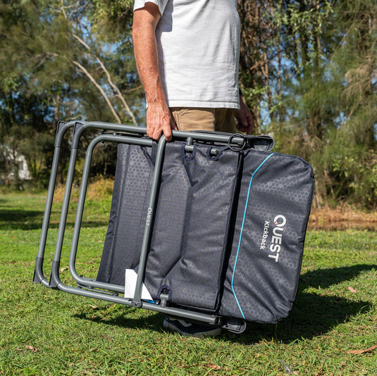 Person holding a Quest Kickback Reclining Chair in a grassy outdoor setting