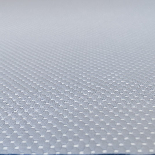 Close-up of a light gray textured surface with a repeating small hexagonal or dotted pattern, filling the frame.