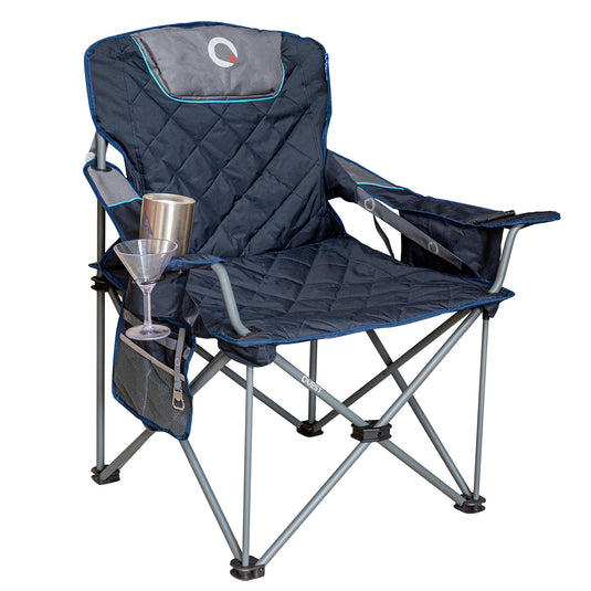 A navy blue quilted folding camp chair with gray metal legs, featuring a side pocket holding a martini glass and a cup, with a gray headrest pillow on a white background.