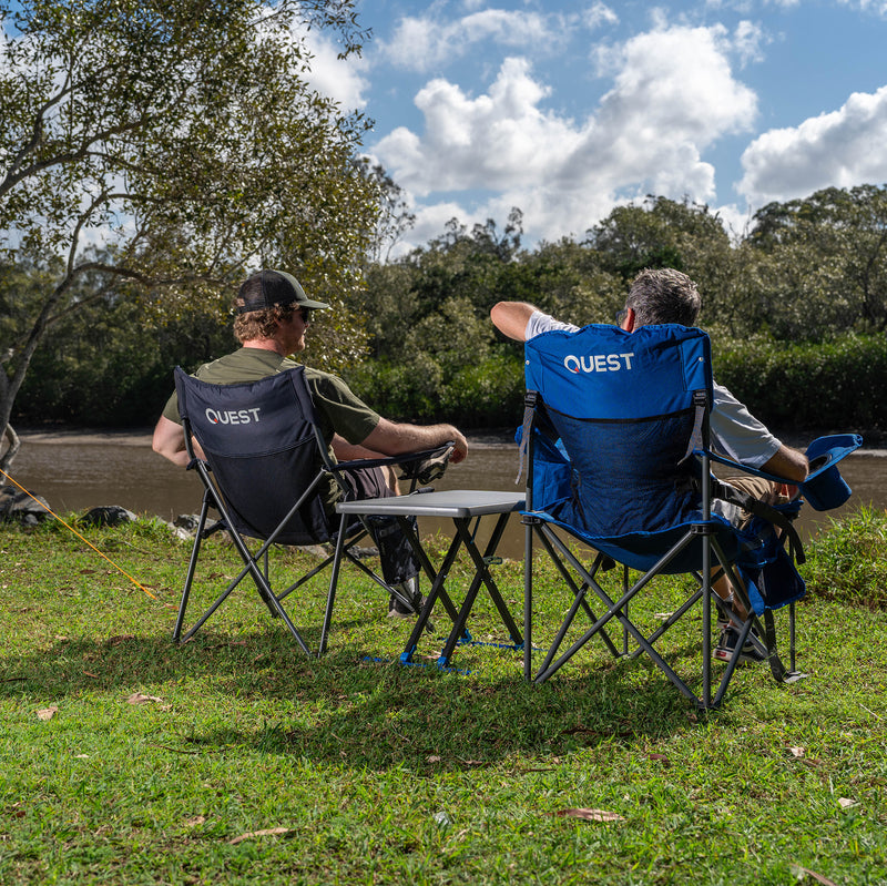 Load image into Gallery viewer, Two people sitting in &#39;Quest&#39; branded camping chairs outdoors with Micro Pack Side Table
