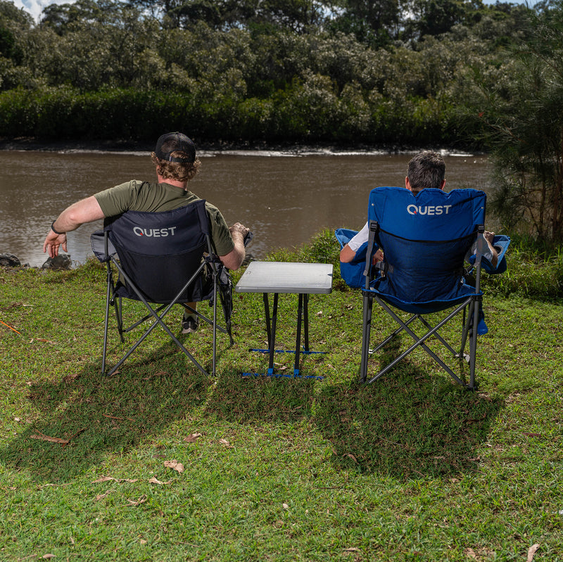 Load image into Gallery viewer, Two people sitting in &#39;Quest&#39; branded camping chairs outdoors with Micro Pack Side Table
