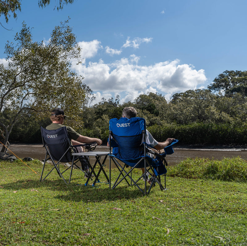 Load image into Gallery viewer, Two people sitting in &#39;Quest&#39; branded camping chairs outdoors with Micro Pack Side Table
